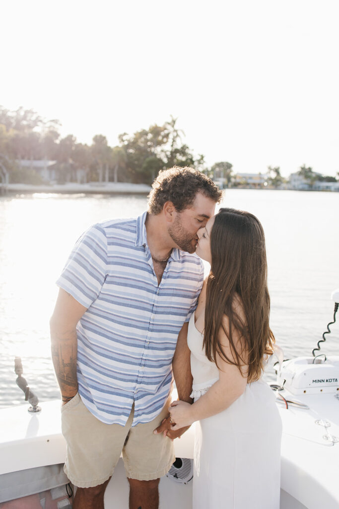man and woman share a kiss during their boat engagement photoshoot