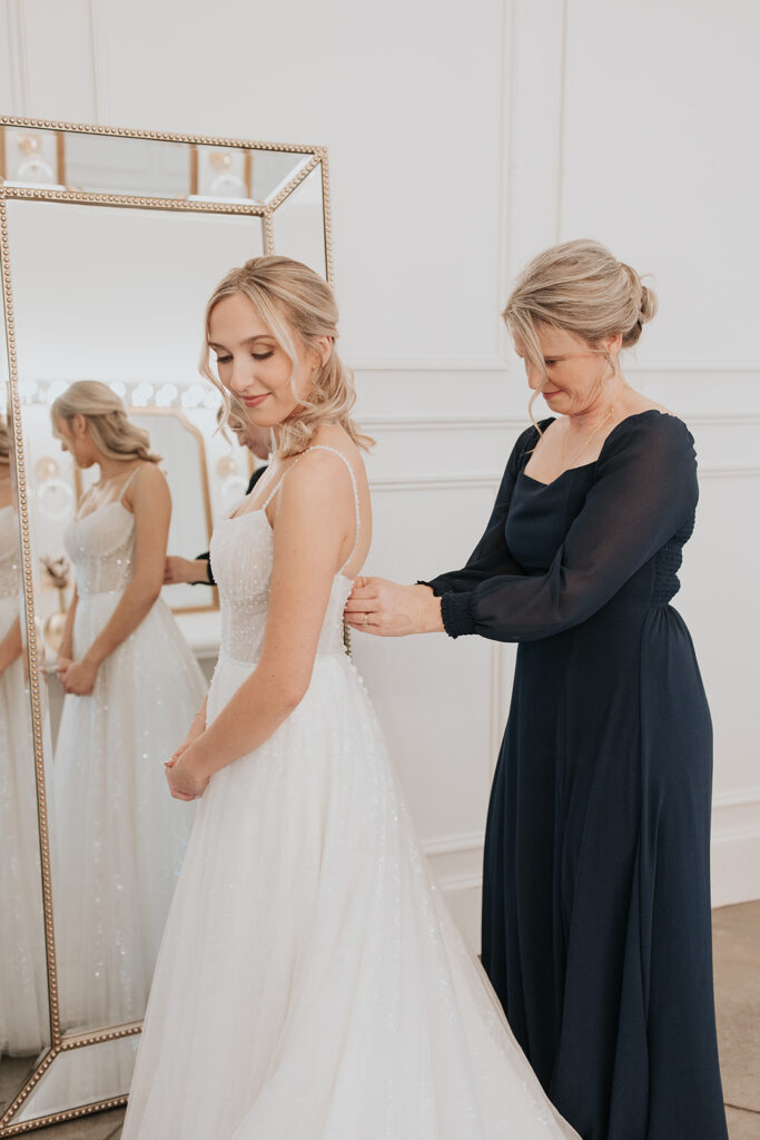 bride's mother helps button up gown