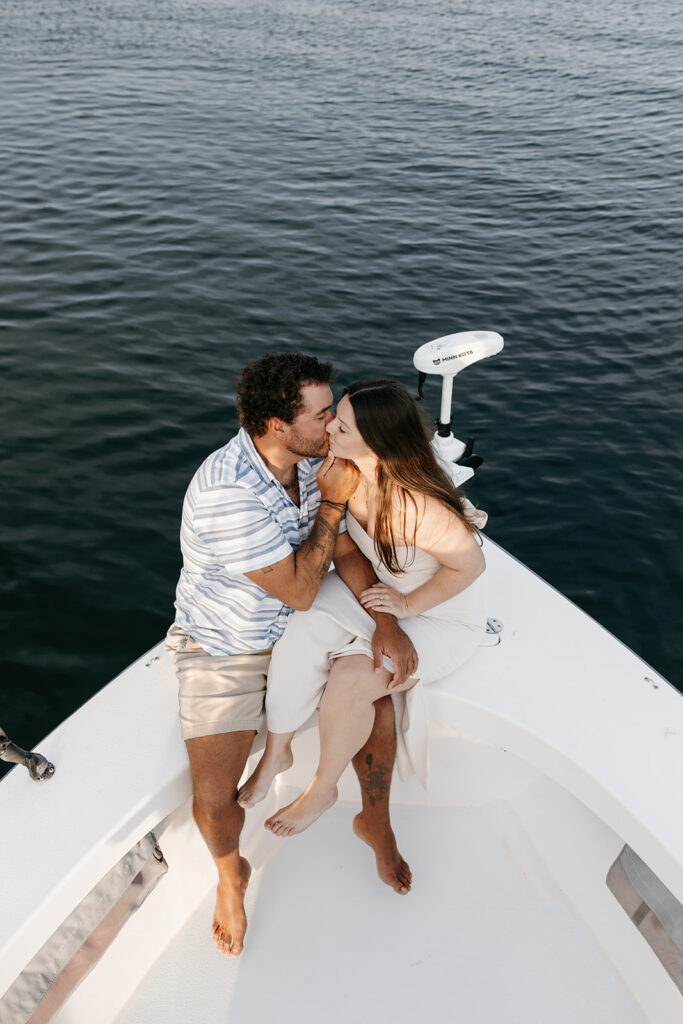 Couple sitting at the bow of their fishing boat for their engagement photos