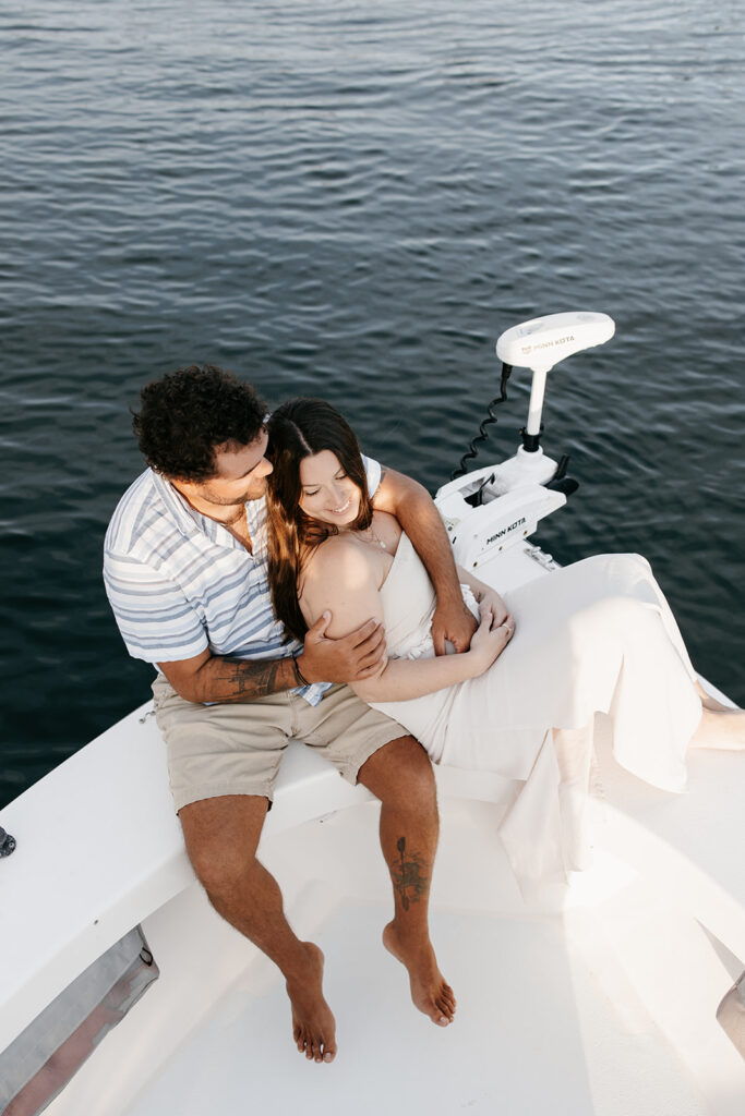 Couple sitting at the bow of their fishing boat for their engagement photos