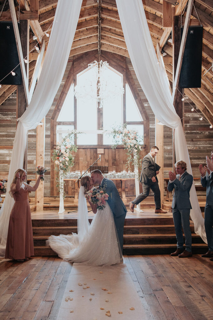 bride and groom kissing on the podium for their Stone Hill Barn wedding
