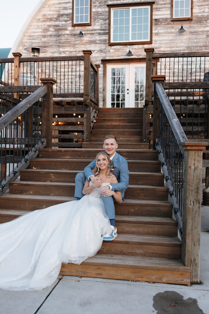 bride and groom sitting on the steps of the Stone Hill Barn