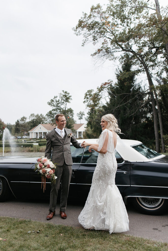Bride and groom stand in front of a restored Cadillac