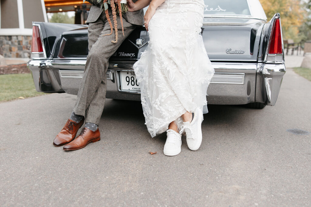 Bride and groom stand in front of a restored Cadillac