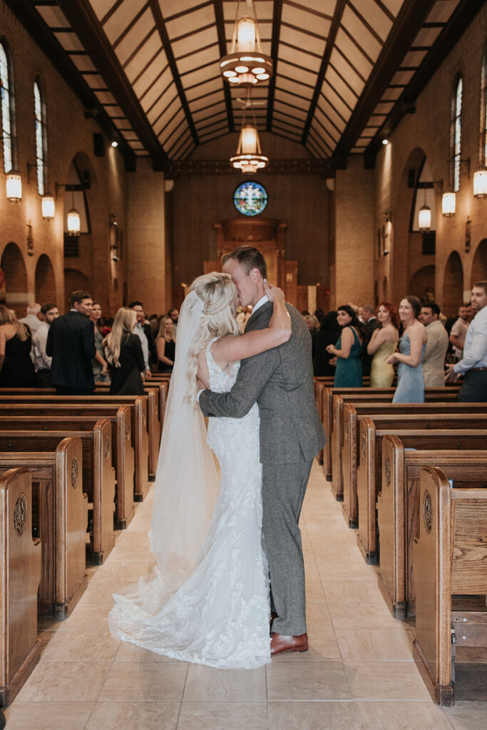 bride and groom kiss in the aisle after wedding ceremony