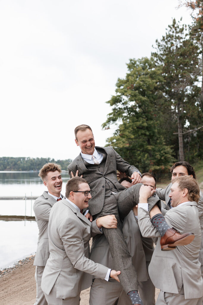 groom and groomsmen mess around on the shore of Gull Lake
