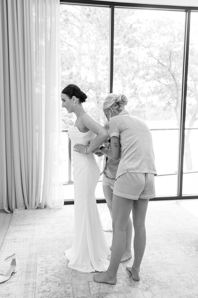 Bridesmaids helping bride with her dress