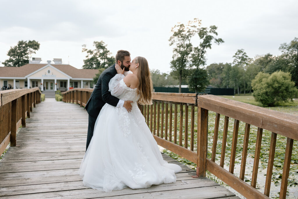 Bride and groom kissing on a dock on a pond with lily pads