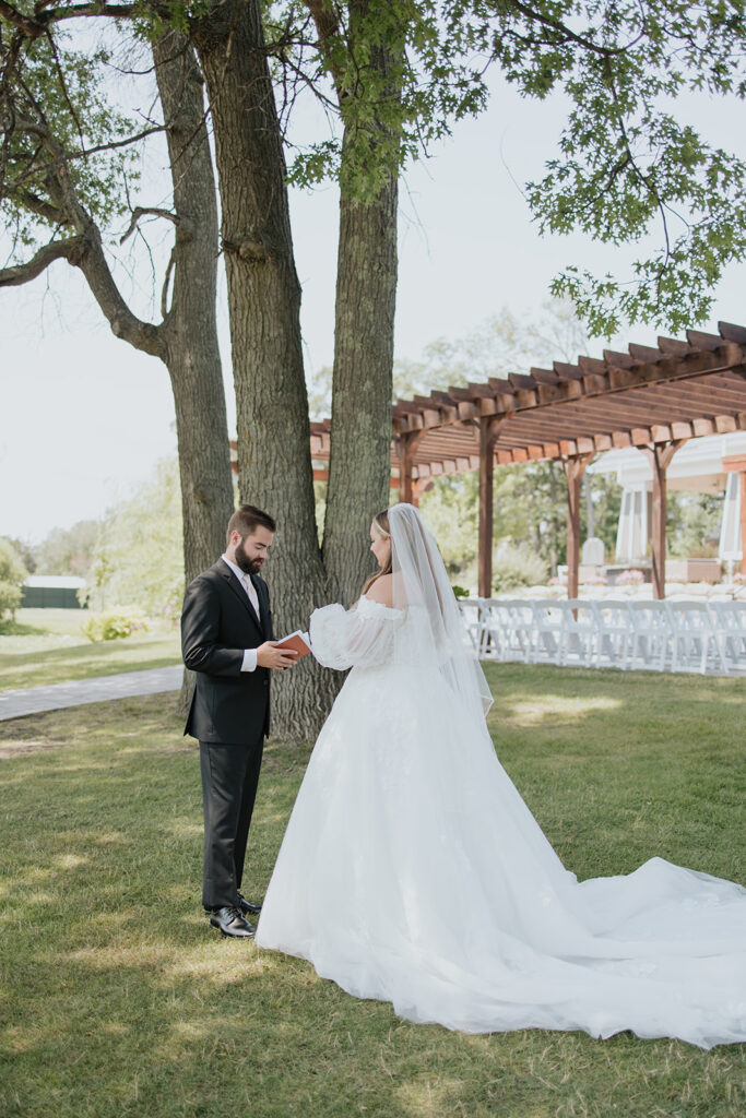 Bride and groom reading private vows on the lawn at Madden's on Gull Lake