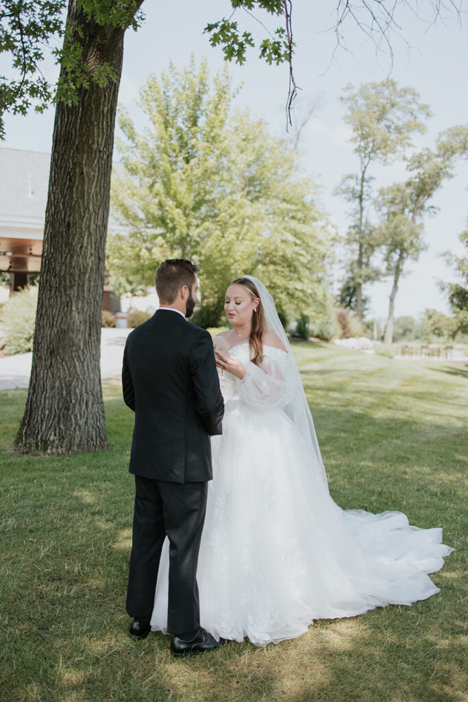 Bride and groom reading private vows on the lawn at Madden's on Gull Lake