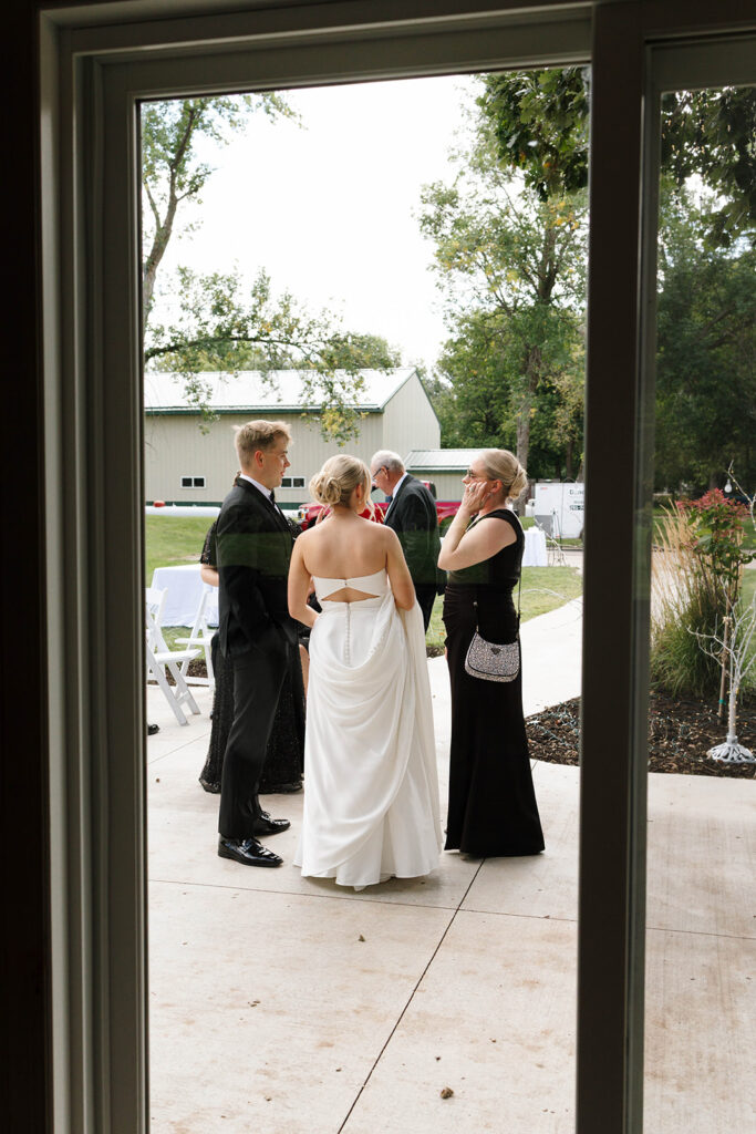 Guests enjoying the outdoor reception under the large tree with hanging lights
