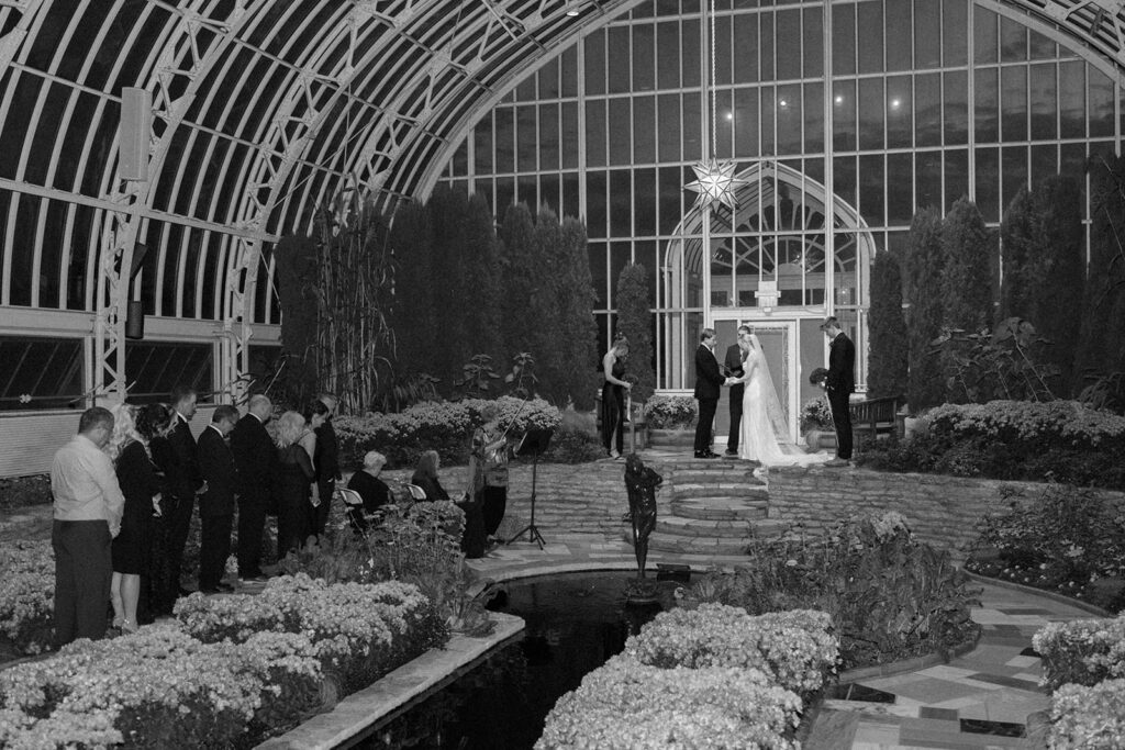 Candid photo taken during a cozy ceremony at a botanical space.
