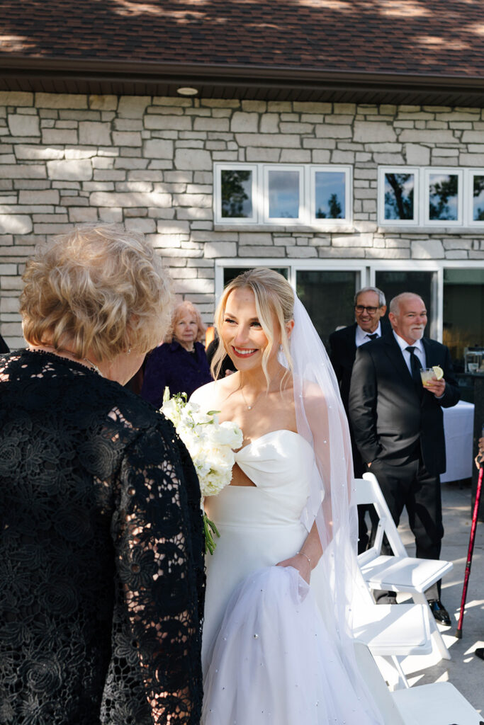 Guests enjoying the outdoor reception under the large tree with hanging lights

