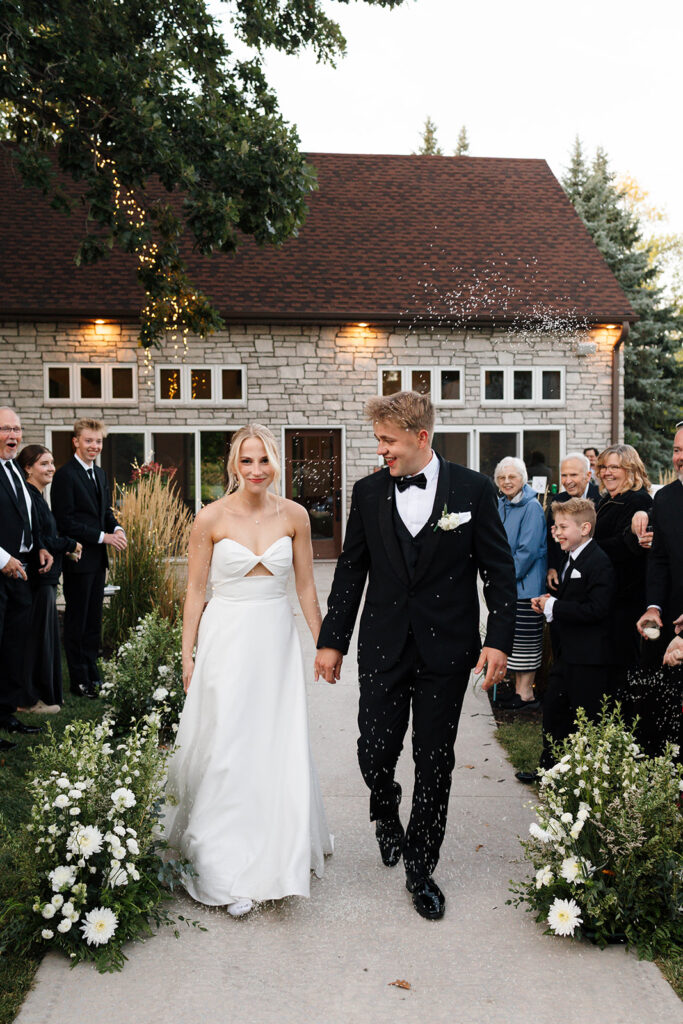 Guests enjoying the outdoor reception under the large tree with hanging lights
