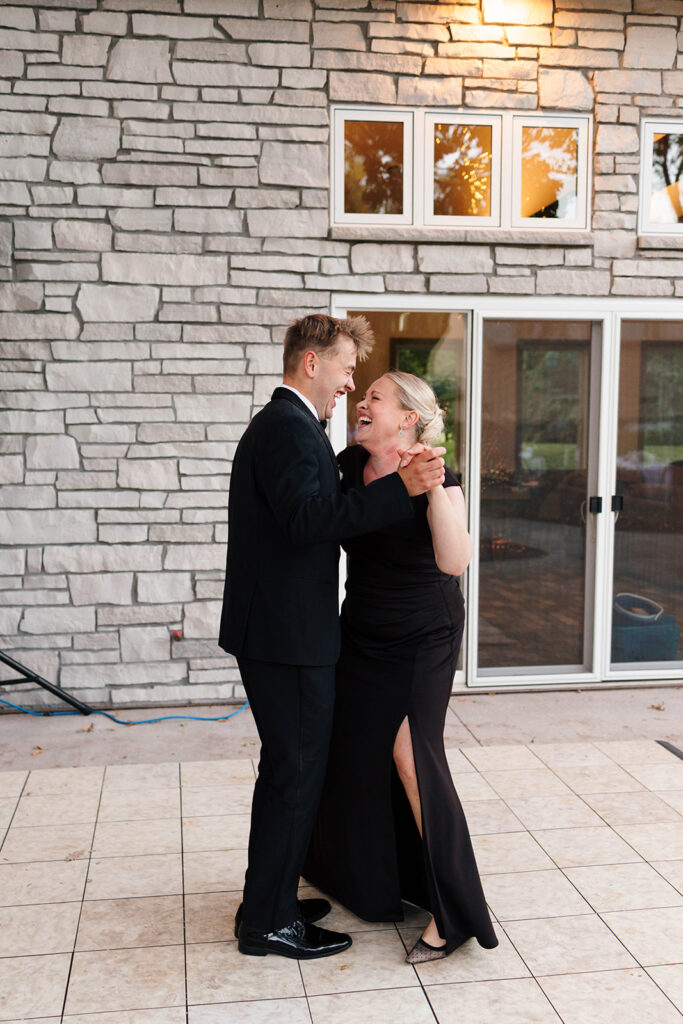 Guests enjoying the outdoor reception under the large tree with hanging lights
