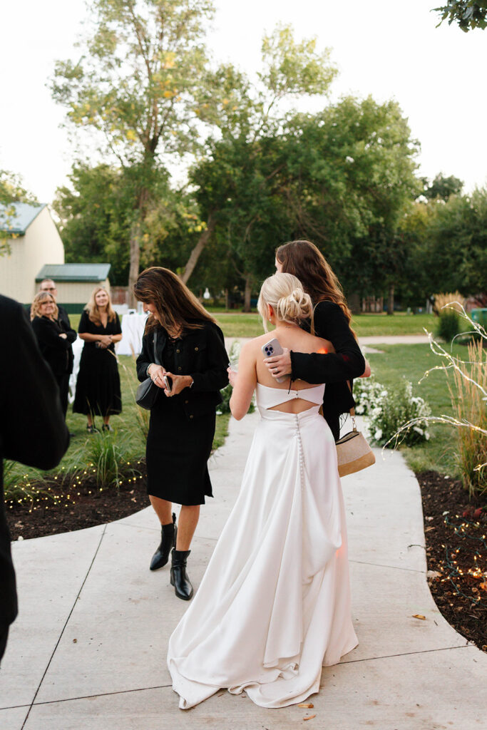 Guests enjoying the outdoor reception under the large tree with hanging lights
