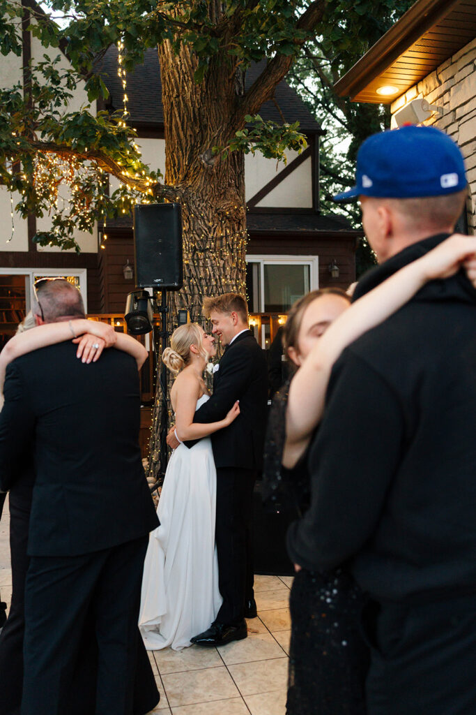 Bride and groom dancing under string lights at their reception

