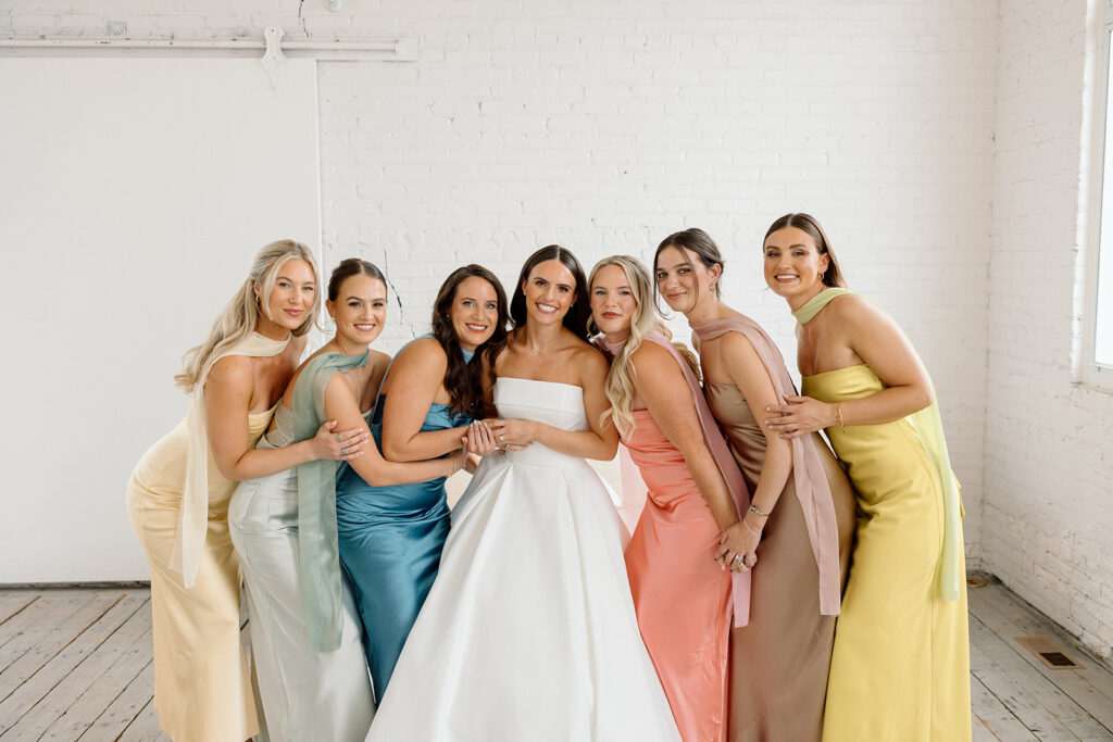 Bridesmaids in colorful dresses holding vibrant bouquets by Bloom Designs
