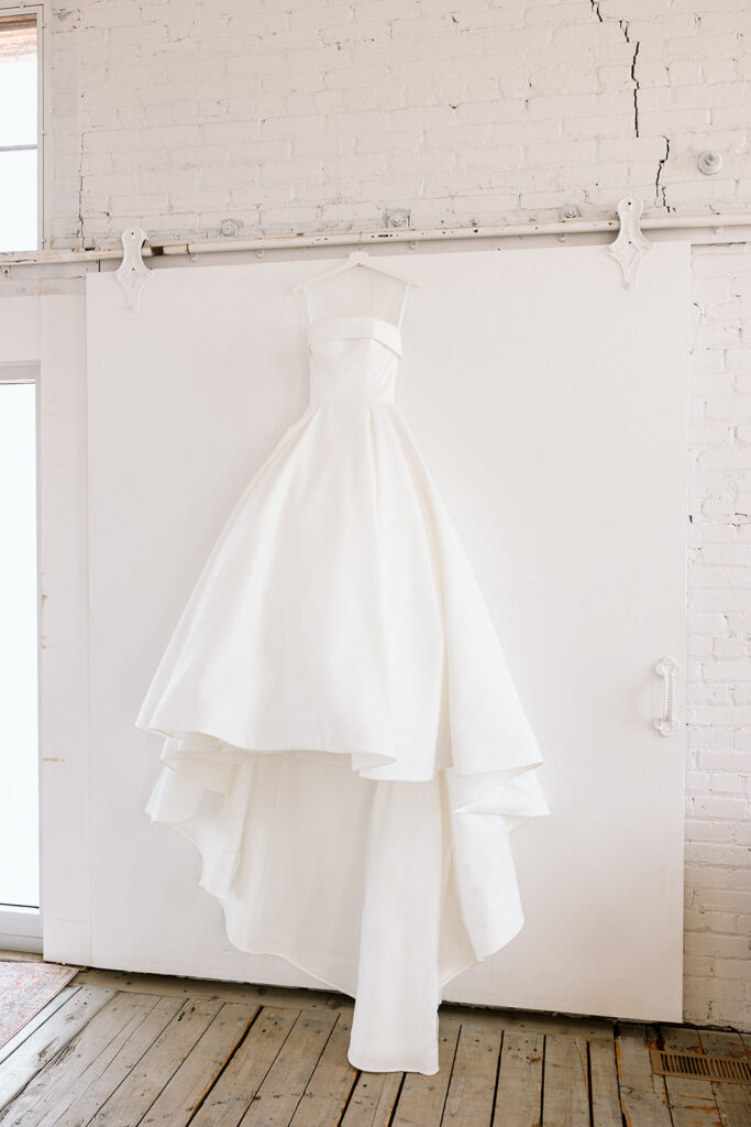 Bride posing in her wedding gown with natural light streaming through the window
