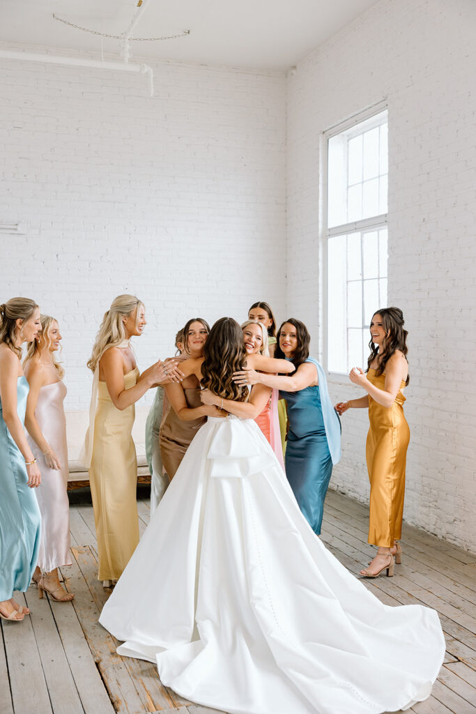 Bridesmaids in colorful dresses holding vibrant bouquets by Bloom Designs
